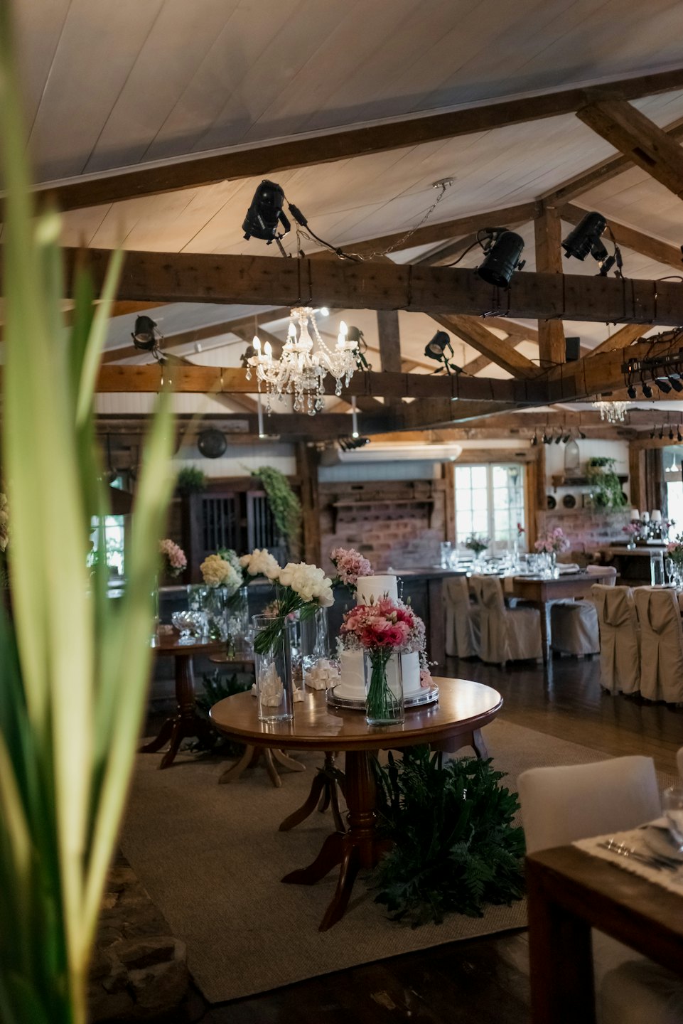 Wedding reception tables with floral arrangements and a cake.