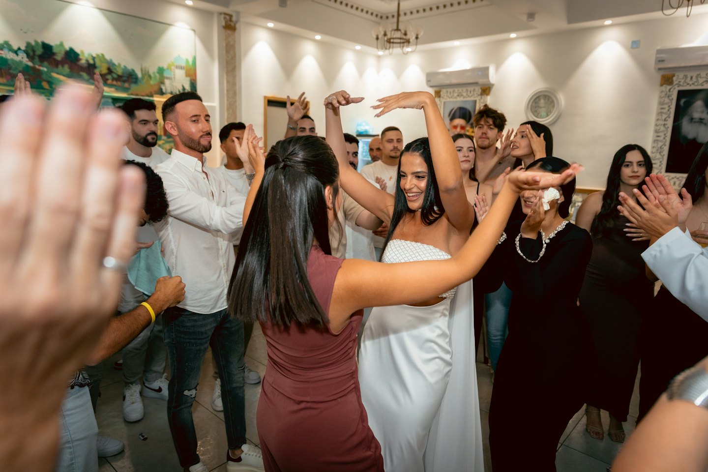Two women dance while friends celebrate at a party.