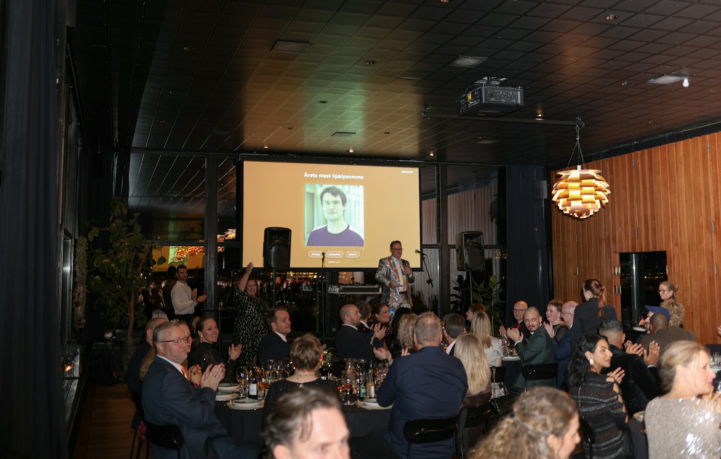 A speaker on stage addresses an audience at a formal gala.