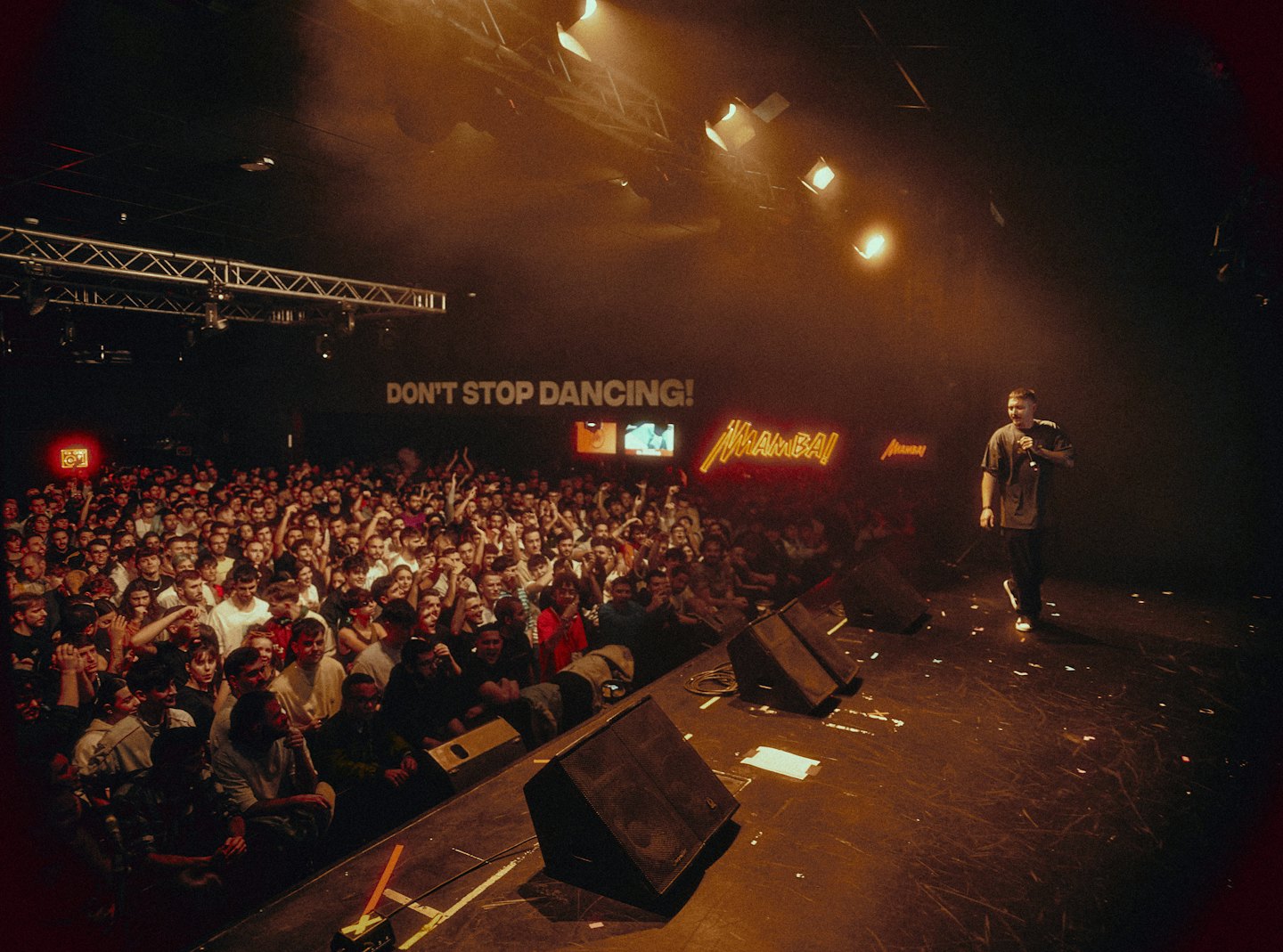 A performer speaks into a microphone before a large crowd.